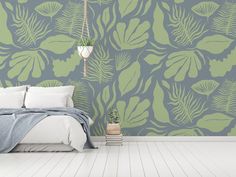 a bedroom with a bed, plant and wallpaper in shades of blue and green