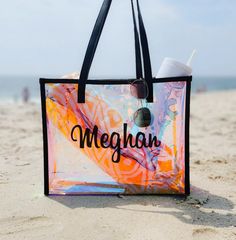 a bag sitting on top of a sandy beach next to the ocean with a cup in it