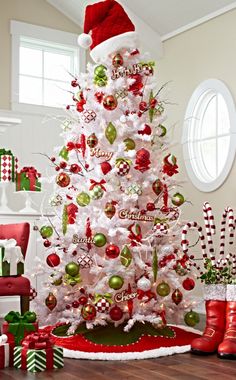 a white christmas tree decorated with red and green ornaments, candy canes, santa's hat