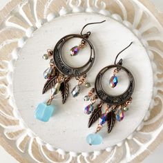 Gorgeous antique bronze earrings with multicolored beads, feather charms and a light blue bead for some color.  Ear wires are nickel and lead free.  3" dangle length 1.25" wide  Please give me 1-3 business days to ship. Shipping to US only. Earrings will ship in a square jewelry box and waterproof poly mailer.  Always feel free to ask questions! Bohemian Crystal Earrings With Adjustable Fit, Bronze Dangle Beaded Earrings For Jewelry Making, Bohemian Metal Beaded Earrings With Ear Wire, Bohemian Czech Glass Crystal Earrings Nickel Free, Bohemian Beaded Earrings With Metal Ear Wire, Bohemian Bronze Beaded Earrings Nickel Free, Adjustable Nickel Free Bronze Beaded Earrings, Bohemian Bronze Chandelier Earrings With Ear Wire, Bohemian Beaded Metal Crystal Earrings