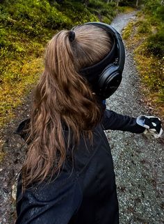 a woman with headphones on walking down a dirt road