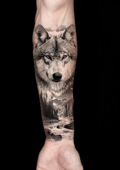 a man's arm with a wolf on it and mountains in the background,