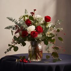 a vase filled with red and white flowers on top of a blue cloth covered table