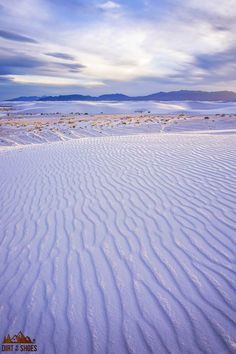 the sky is filled with clouds and white snow in this desert landscape, as well as mountains