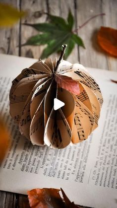 an origami pumpkin sitting on top of a book with music sheets and leaves around it