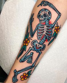 a person with a tattoo on their arm that has a skeleton and flowers on it