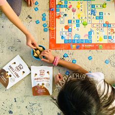 two children are playing scrabble together on the floor with their hands in a bowl