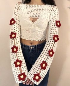 a woman standing in front of a wall wearing a white top with red flowers on it