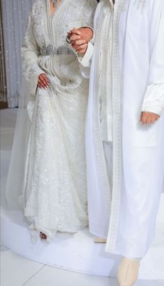 two people dressed in white standing next to each other