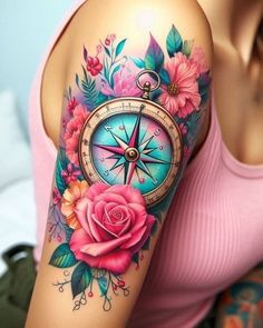 a woman's arm with flowers and a compass tattoo on her left shoulder,