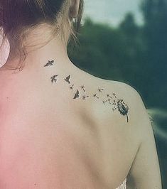 the back of a woman's neck with a dandelion tattoo