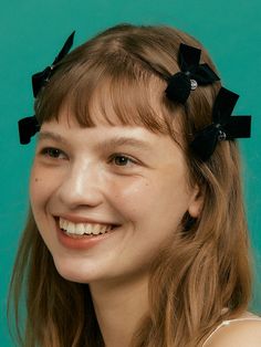 a woman with long hair wearing black bows on her head and smiling at the camera