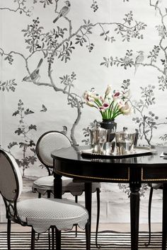 a dining room table with chairs and a vase filled with flowers on top of it