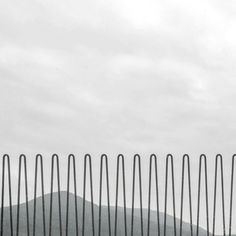 a black and white photo of a fence with mountains in the background