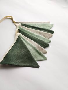 four green and white pieces of cloth hanging from a string on a white tablecloth