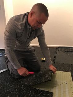 a man sitting on the floor working on a piece of paper with a ruler in front of him