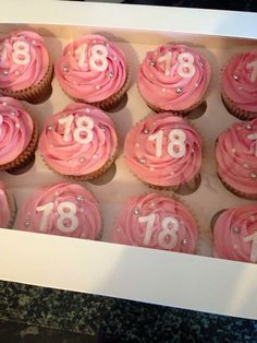 cupcakes with pink frosting and white numbers in a box