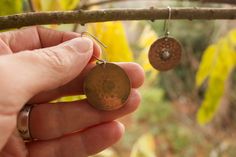 Meditatively hand stamped pure copper discs dangle from hand formed sterling silver ear hooks with a hand formed sterling silver center. Total length is 1 3/4 inches. Rustic and rhythmically styled showing the unique quality of a handmade original. A patina has been added bring depth to the stamped design and add to the rustic style.. I find these have a nice thickness to them and a good weight- each earring weights approximately .10 oz (3g) Brass Flower Earrings Gift, Bohemian Bronze Plug Earrings, Bohemian Bronze Round Plug Earrings, Bronze Bohemian Plug Earrings, Bronze Bohemian Round Plug Earrings, Circular Festival Earrings With Hooks, Handmade Medallion Earrings For Gift, Handmade Medallion Earrings As Gift, Brass Round Flower Earrings