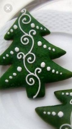 two green christmas trees on a white plate with swirly designs around the top and bottom