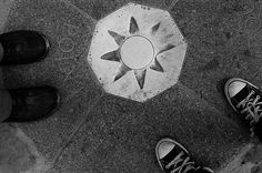 two people standing in front of an upside down umbrella on the ground with their feet up