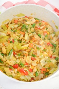 a white bowl filled with vegetables on top of a checkered tablecloth covered table