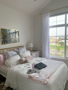 a bedroom with a large window and white bedding