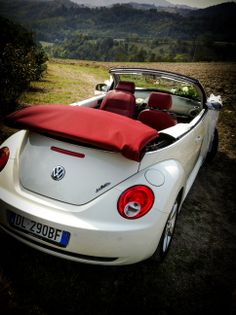 the back end of a white car with a red seat cover on it's roof