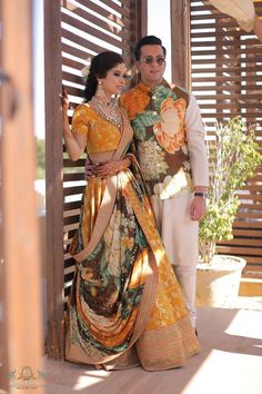 a man and woman standing next to each other in front of a wooden structure with shutters