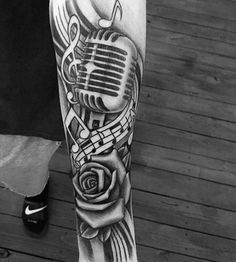 a black and white photo of a man's leg with a microphone, rose and music notes