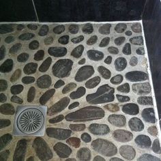 a stone shower with a drain in the middle and rocks on the floor next to it