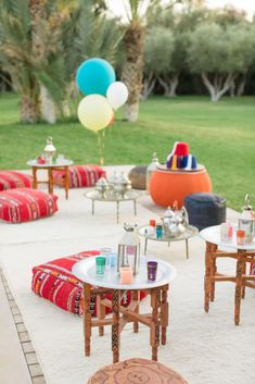 tables and chairs are set up in the middle of an outdoor area with colorful balloons