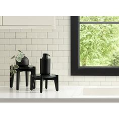 three black vases sitting next to each other in front of a window