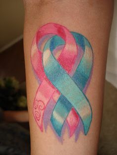 a pink and blue ribbon tattoo on the leg