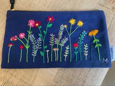 a blue bag with embroidered flowers on it