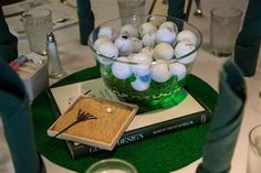 a glass bowl filled with golf balls sitting on top of a green tablecloth covered table