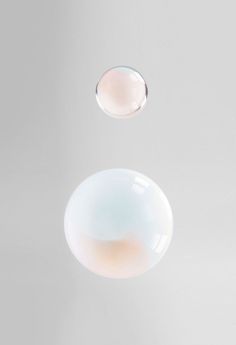 two bubbles floating in the air on a white surface with no one around them,