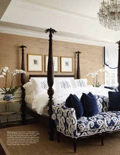 a bedroom with four poster bed, chandelier and blue couch in the corner