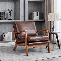 a brown leather chair sitting in front of a book shelf next to a lamp and table