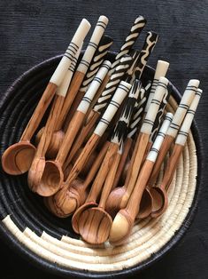 wooden spoons are arranged in a bowl with zebra print designs on them, along with black and white utensils