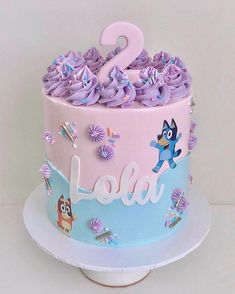 a two tiered cake with purple frosting and decorations on the top is decorated with cartoon characters