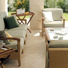 a living room with wicker furniture and green pillows on the couches next to each other