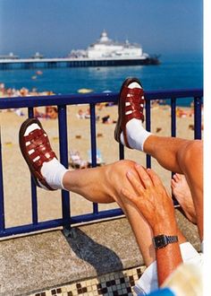 two people are sitting on the beach with their feet up against each other's legs