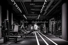 an empty gym with rows of machines and treadmills in black and white photo