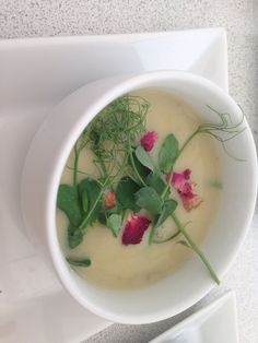 a white bowl filled with soup and garnished with green leafy toppings