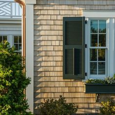 an image of a house with shutters on the windows and plants in the window boxes