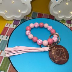 a pink and white beaded bracelet with a tassel hanging from it's end