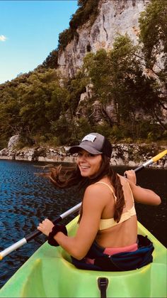 a woman in a yellow and black hat is paddling a kayak on the water