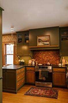 a kitchen with green cabinets and wood floors, an area rug on the wooden floor