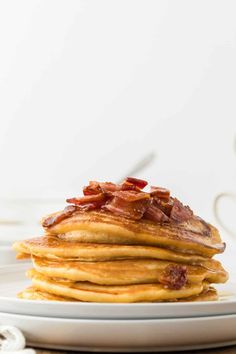 a stack of pancakes with bacon on top