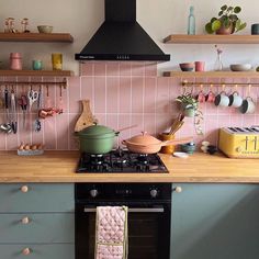 a stove top oven sitting inside of a kitchen next to a counter with pots and pans on it